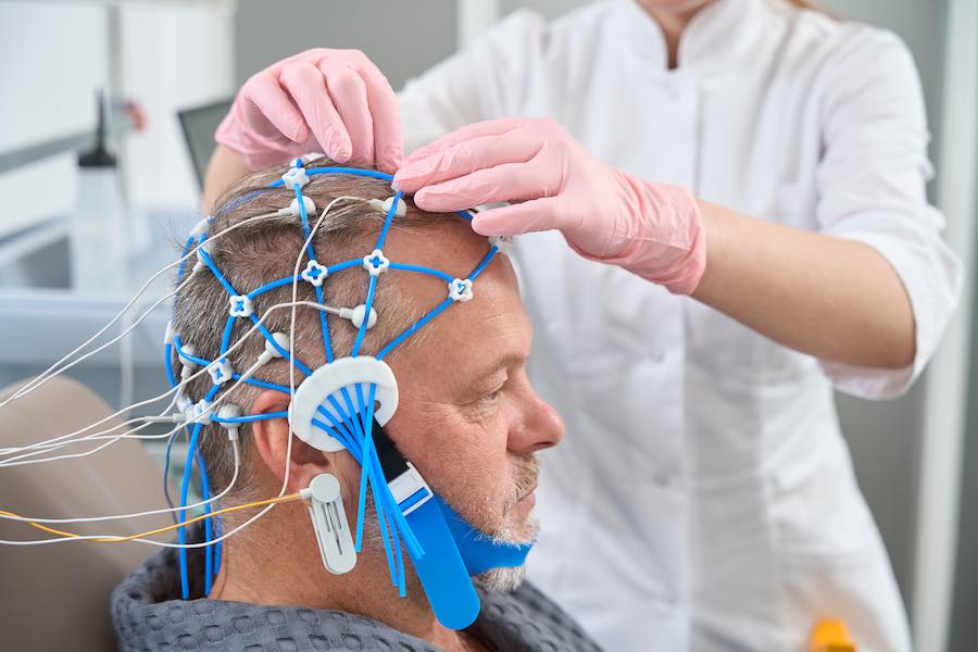 Diagnostician doctor attaches electrodes to the patient head a man goes through a checkup in a medical center